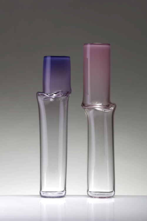Two blown glass cylindrical pieces with purple and pink tone tops, part of the Torsion series investigating the materiality of glass.