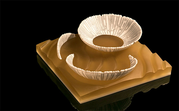 Bob Leatherbarrow cast glass artwork. Small broken bowls are “washed up” on a sandy shore in this piece called 'Flotsam'.
