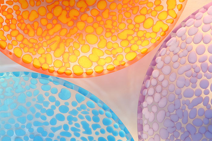 Rounded “pebbles” rimmed by darker colours appear to float in clear glass. Bowls made by Bob Leatherbarrow.