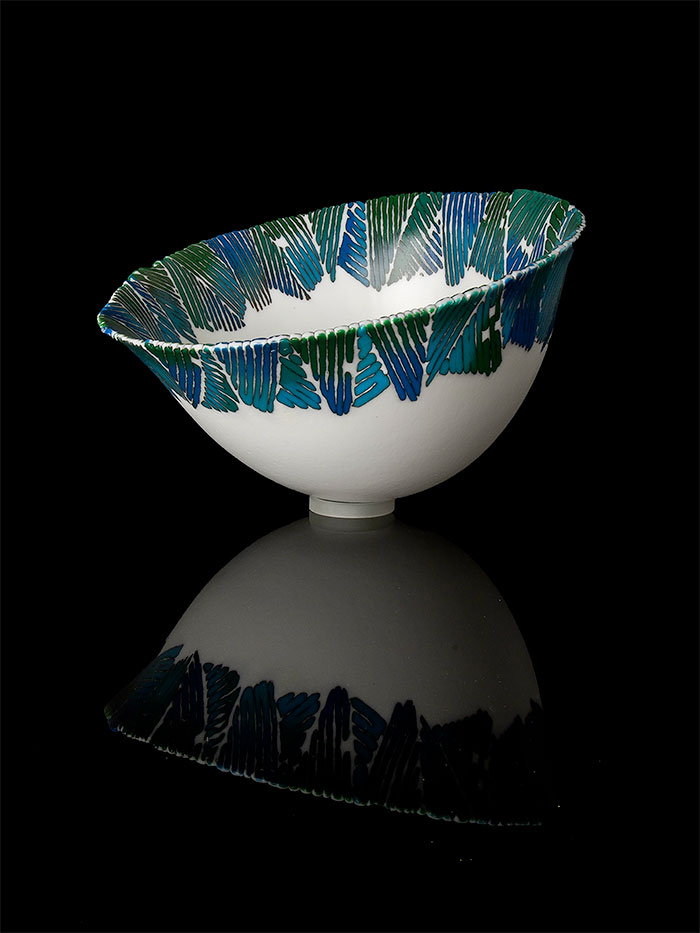 Textured powders form linear patterns with organic outlines around the rim of this deep vessel.