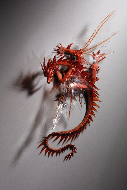 A wall art sculpture of a dragon made from bronze and flameworked glass.