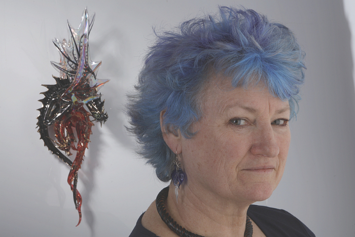 Lampworking glass artist Sandra Young in front of one of her dragon sculptures.