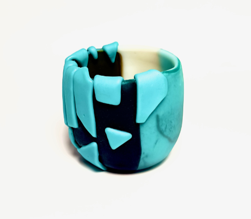 Uneven glass vessel in solid block colours including black, aqua and cream with applied 3D effects.