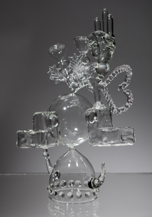 Clear glass sculpted into a variety of balanced components including a viking helmet and a heart. Titled 'Cultural Exchange'. 