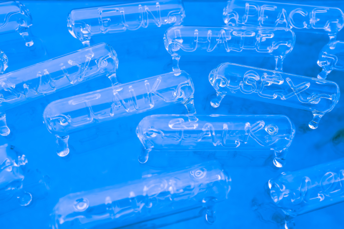 Scientific glass tubes on legs containing glass lampworked words.