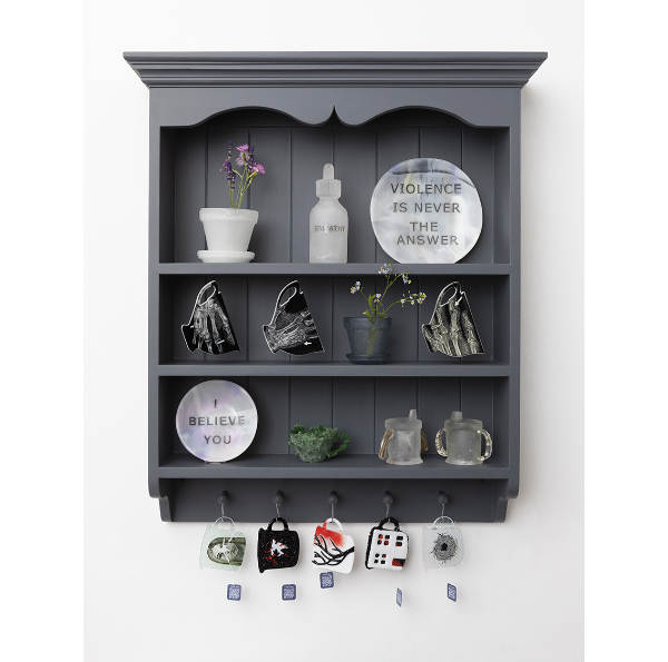 A wall cabinet in grey featuring assorted objects like cups and baby beakers with etched slogans.