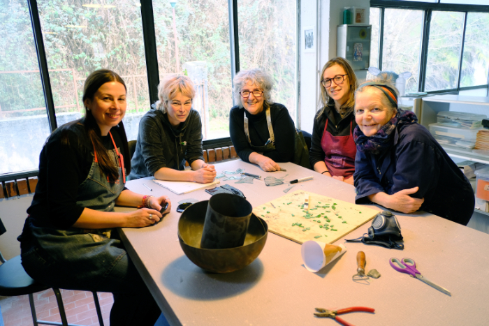 Five women of the Broken Home Collective group working round a table.