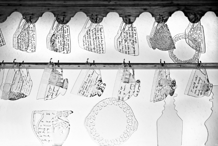 Detail of 'Fragment Dresser' glass and light installation showing close-up of flat clear glass etched cups, jug, plate etc.