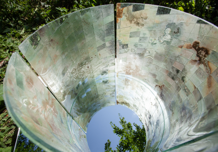 A cylindrical glass light well made of mosaic-effect tiled glass in pearlised and natural tones to reflect the experience of place and time at the quarry. A mirror beneath reflects the sky.
