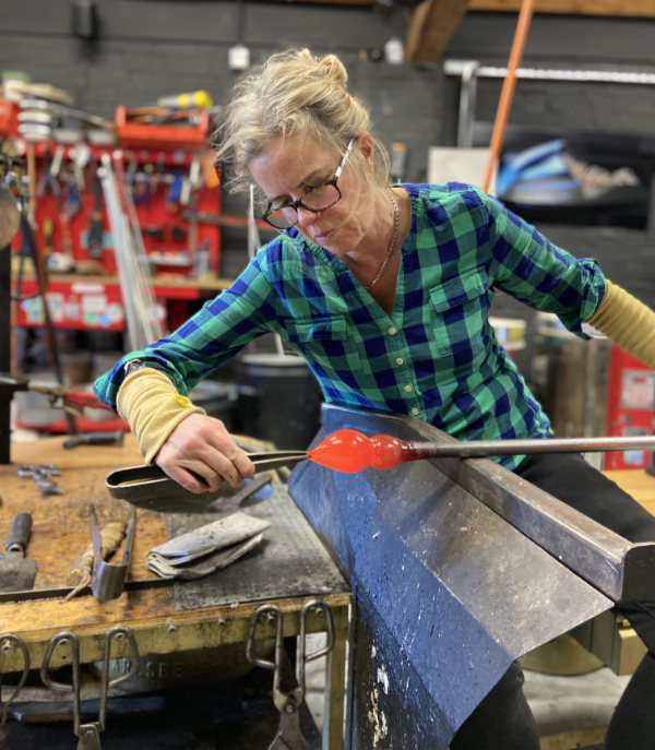 Glass artist Michele Oberdieck shaping molten glass in the studio.