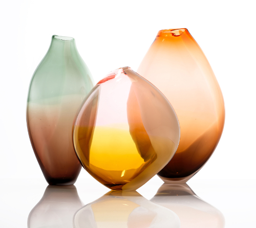 Three blown glass vessels in pastel colours.