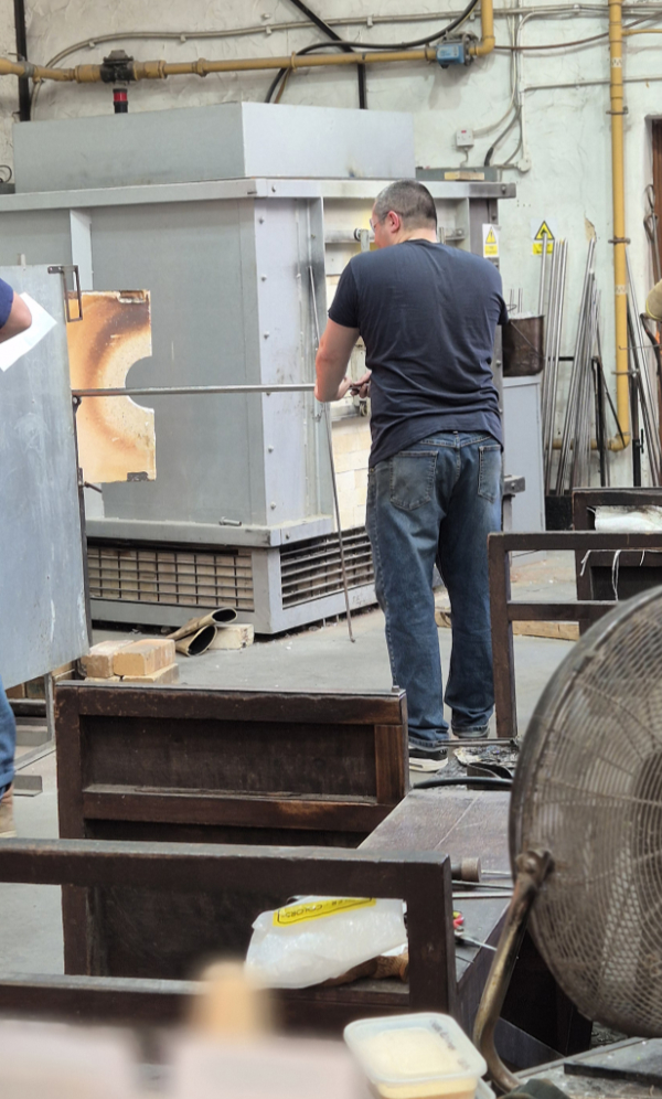 Theo Brooks holding glass inside the glory hole as he forms a new mask design.